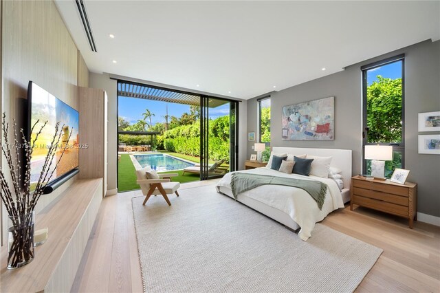 living room featuring a high ceiling, light hardwood / wood-style floors, and a wall of windows