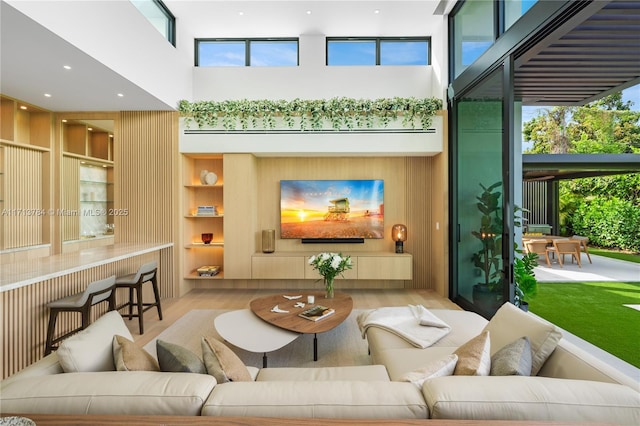 living room with a towering ceiling, wooden walls, and light wood-type flooring