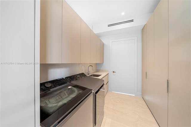 kitchen featuring sink, washing machine and dryer, and cream cabinetry