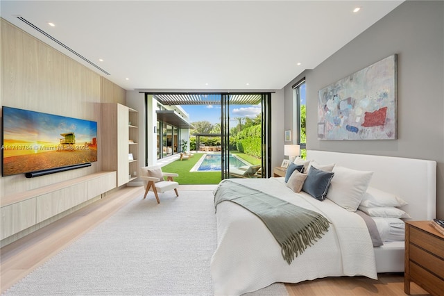 bedroom with expansive windows, access to outside, and light hardwood / wood-style floors