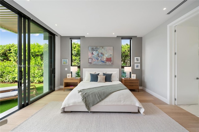 bedroom with expansive windows, access to exterior, and light hardwood / wood-style flooring