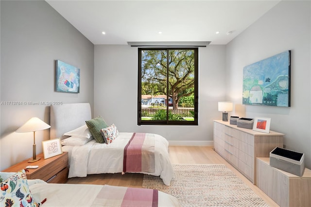 bedroom with a wall of windows and light hardwood / wood-style flooring