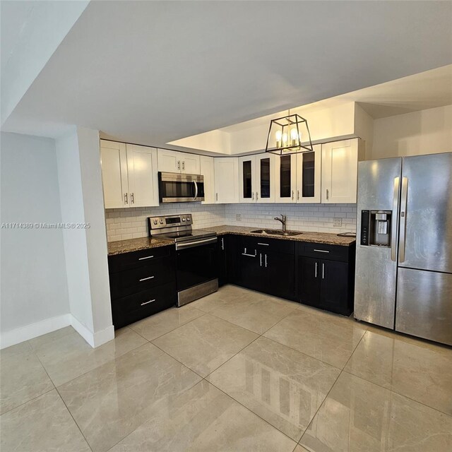 kitchen featuring sink, stainless steel appliances, white cabinets, and dark stone countertops