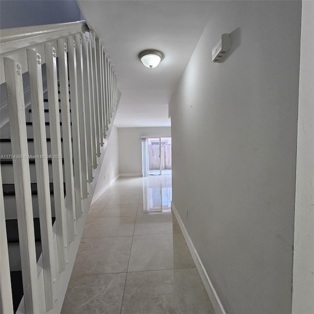 hallway featuring stairway, tile patterned flooring, and baseboards