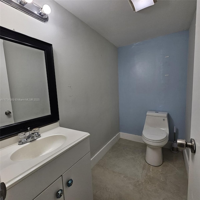 bathroom featuring baseboards, vanity, and toilet