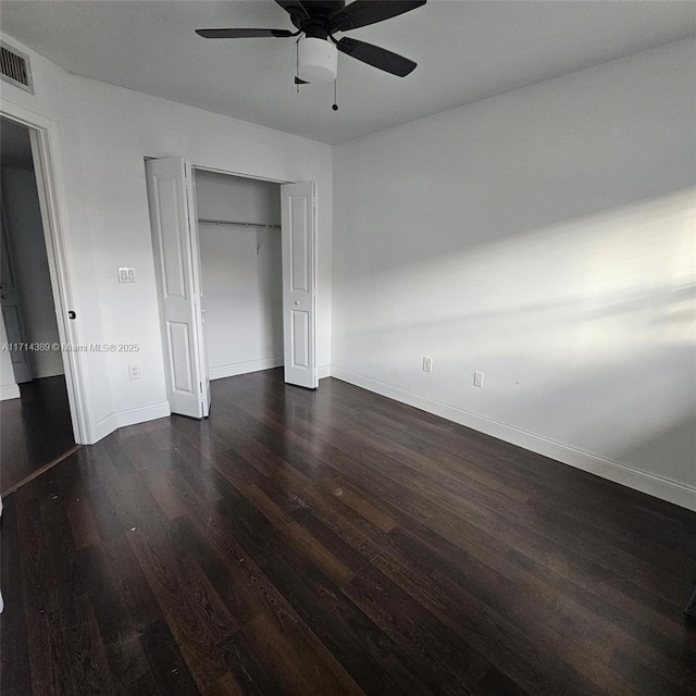 unfurnished bedroom featuring a closet, visible vents, dark wood-type flooring, ceiling fan, and baseboards