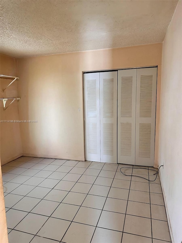 unfurnished bedroom featuring a textured ceiling, a closet, and light tile patterned flooring