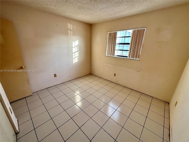 tiled spare room featuring a textured ceiling