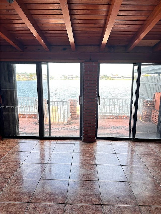 interior space featuring a healthy amount of sunlight, a water view, wooden ceiling, and beamed ceiling