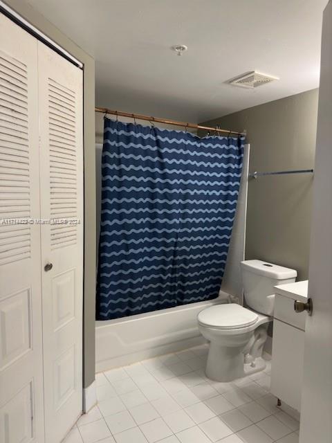 bathroom featuring tile patterned flooring, shower / bath combo, and toilet