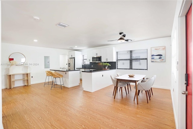 kitchen featuring appliances with stainless steel finishes, a kitchen breakfast bar, ceiling fan, white cabinets, and a center island