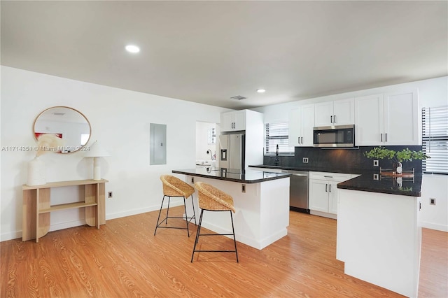 kitchen with a center island, stainless steel appliances, light hardwood / wood-style flooring, electric panel, and white cabinets