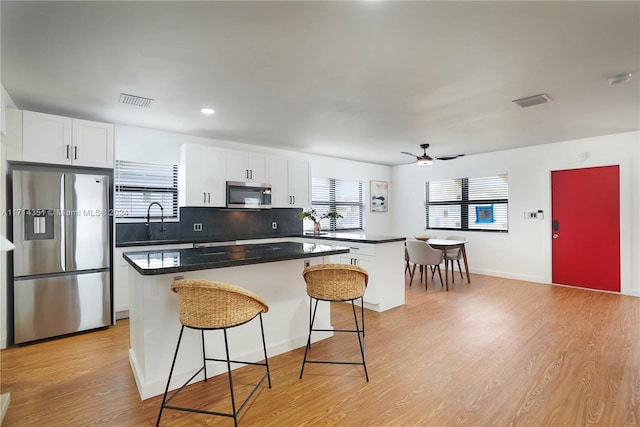 kitchen featuring a breakfast bar, white cabinets, ceiling fan, appliances with stainless steel finishes, and a kitchen island