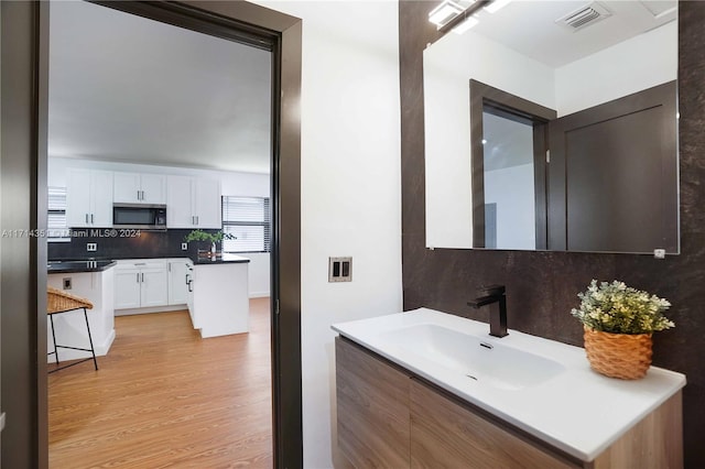 bathroom featuring hardwood / wood-style flooring, decorative backsplash, and sink