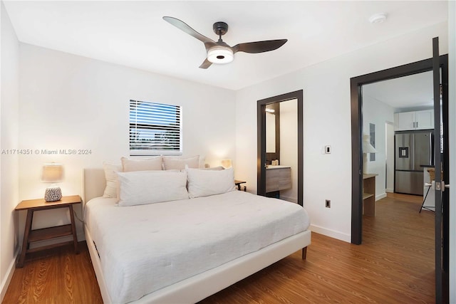 bedroom featuring hardwood / wood-style floors, ceiling fan, stainless steel refrigerator with ice dispenser, and connected bathroom