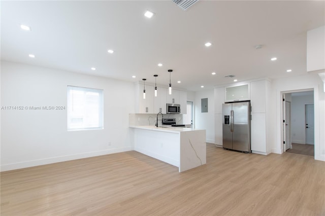 kitchen with white cabinets, hanging light fixtures, light hardwood / wood-style flooring, appliances with stainless steel finishes, and kitchen peninsula