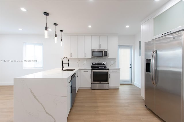 kitchen featuring kitchen peninsula, appliances with stainless steel finishes, white cabinetry, and pendant lighting