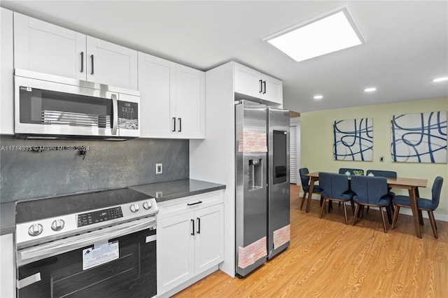 kitchen featuring backsplash, white cabinetry, light wood-type flooring, and appliances with stainless steel finishes