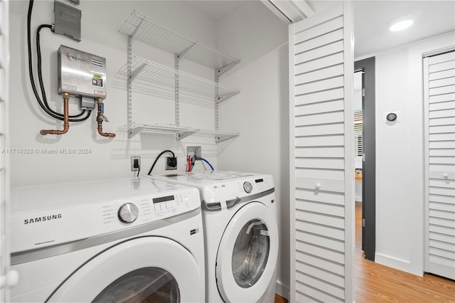 washroom featuring water heater, independent washer and dryer, and light hardwood / wood-style flooring