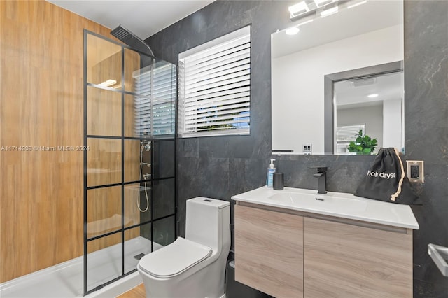 bathroom with vanity, a shower with shower door, tile walls, and toilet