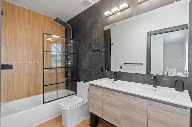 full bathroom featuring enclosed tub / shower combo, hardwood / wood-style floors, toilet, vanity, and tile walls