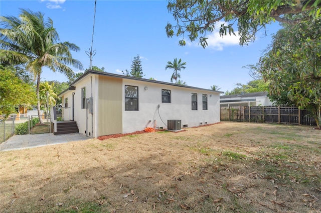 back of property featuring central AC unit and a lawn