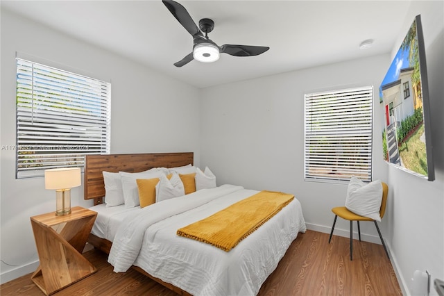 bedroom featuring multiple windows, hardwood / wood-style floors, and ceiling fan