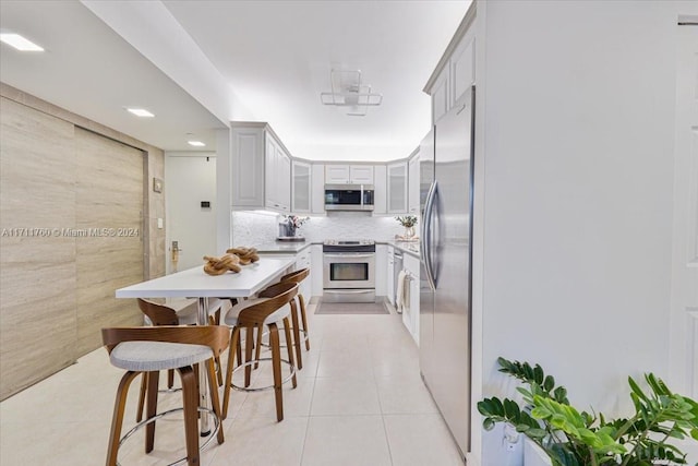 kitchen with appliances with stainless steel finishes, tasteful backsplash, and light tile patterned floors