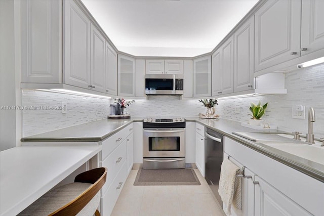 kitchen with light tile patterned floors, sink, appliances with stainless steel finishes, and tasteful backsplash