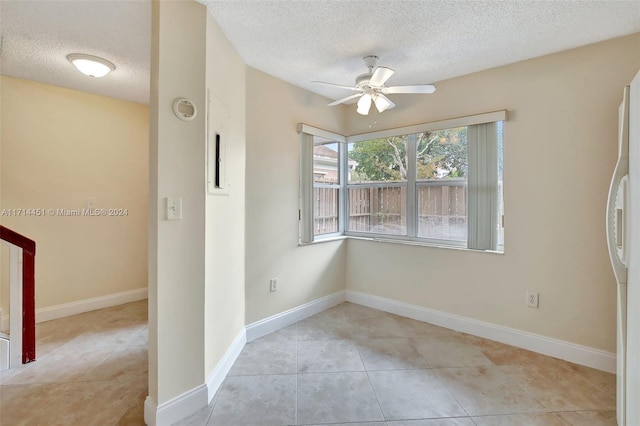 tiled empty room featuring ceiling fan and a textured ceiling