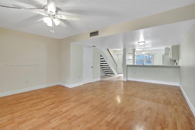 unfurnished living room featuring light hardwood / wood-style floors, a textured ceiling, and ceiling fan