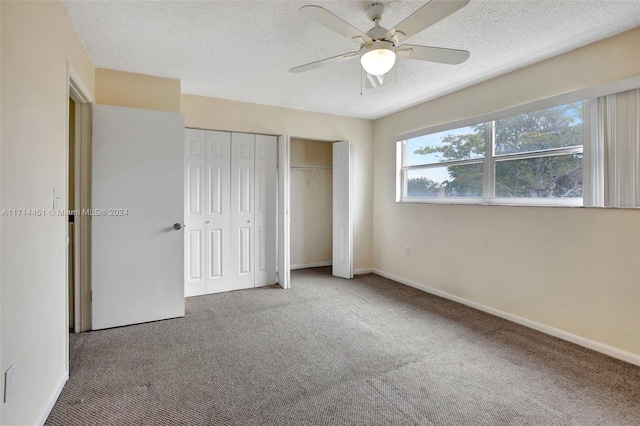 unfurnished bedroom featuring ceiling fan, carpet, a textured ceiling, and two closets