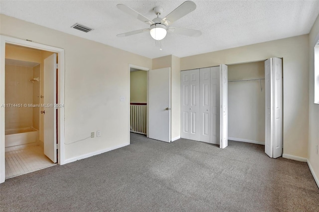 unfurnished bedroom with carpet, a textured ceiling, two closets, connected bathroom, and ceiling fan