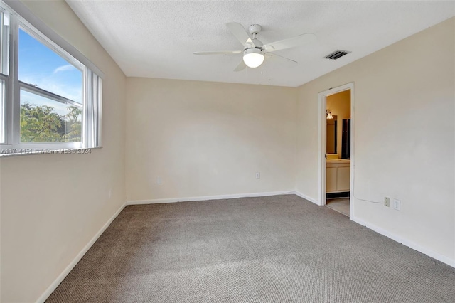 carpeted spare room with ceiling fan and a textured ceiling