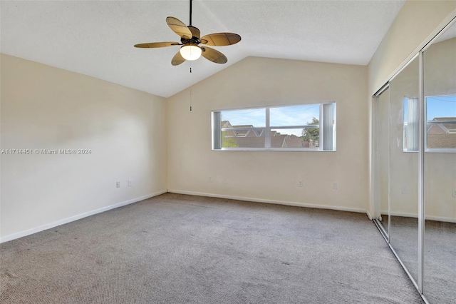 unfurnished bedroom with ceiling fan, vaulted ceiling, carpet, and a closet