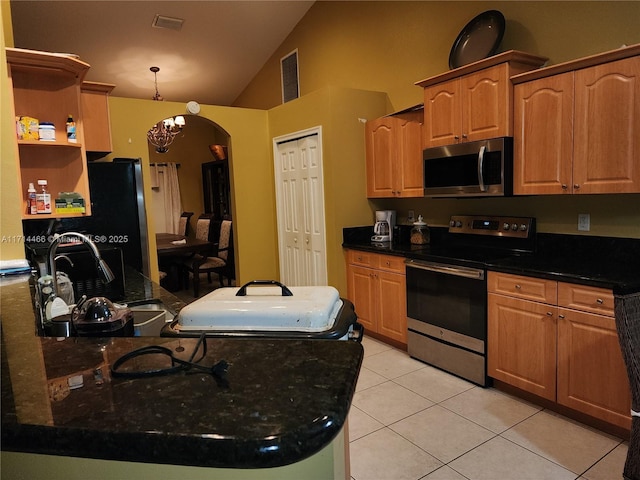 kitchen with appliances with stainless steel finishes, sink, light tile patterned floors, dark stone countertops, and a chandelier