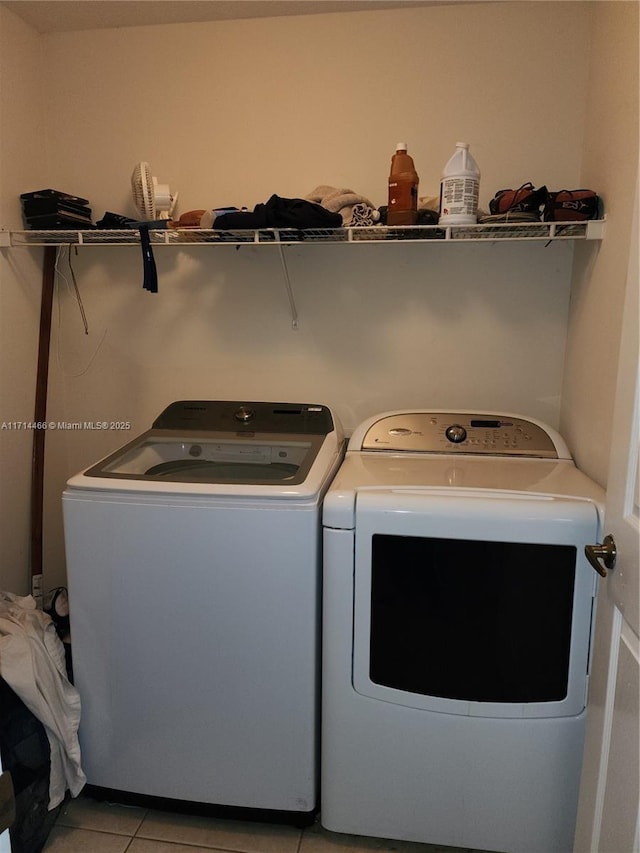 clothes washing area with washer and clothes dryer and light tile patterned flooring