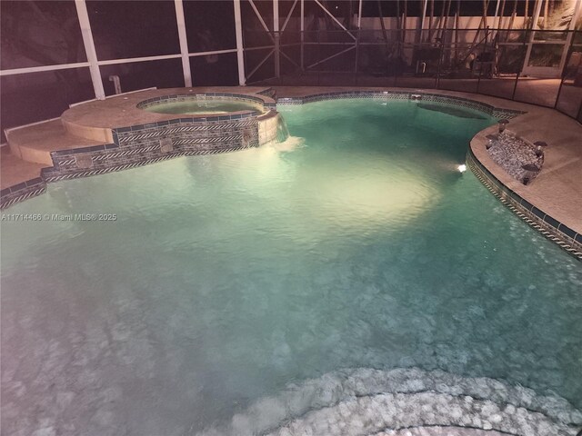 view of swimming pool with an in ground hot tub and a lanai