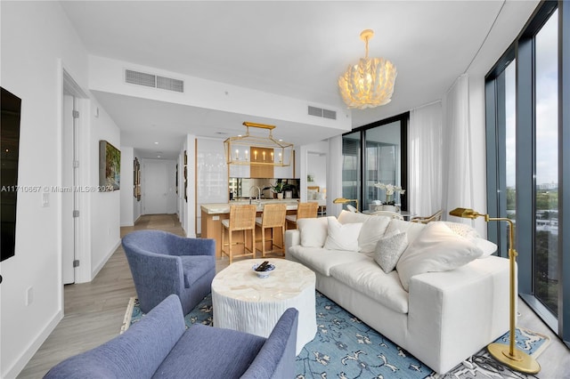 living room with a chandelier, light hardwood / wood-style floors, and expansive windows