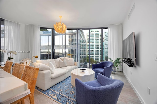 living room with a wealth of natural light, light hardwood / wood-style flooring, expansive windows, and an inviting chandelier