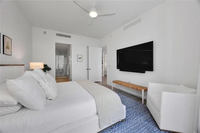 bedroom with ceiling fan, ensuite bathroom, and wood-type flooring