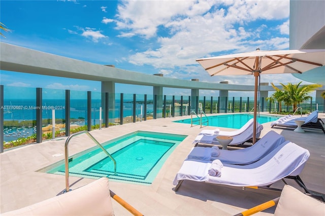 view of swimming pool featuring a patio area, a water view, and a hot tub