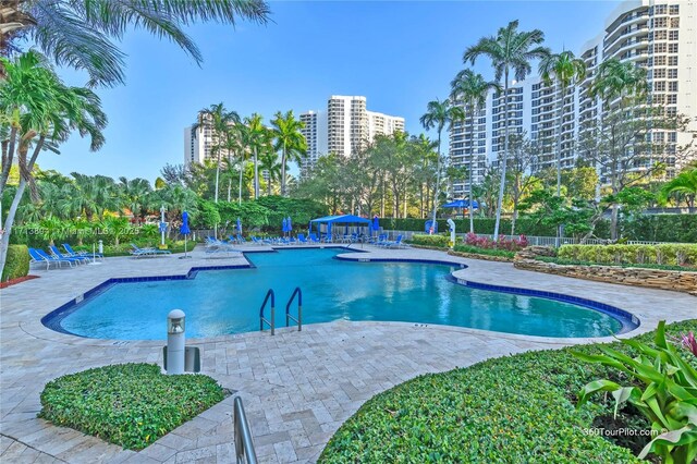 community pool featuring a city view, a patio area, and fence