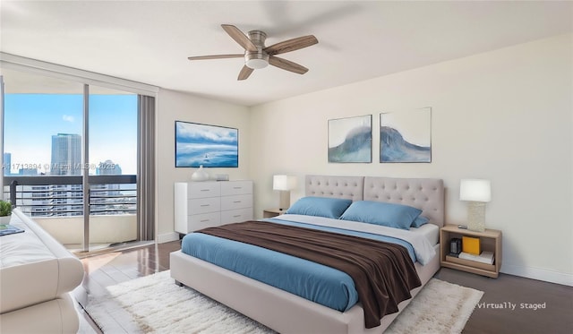 bedroom featuring a city view, baseboards, a ceiling fan, wood finished floors, and expansive windows