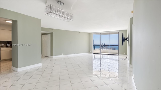 unfurnished room featuring light tile patterned floors, baseboards, and a wall of windows