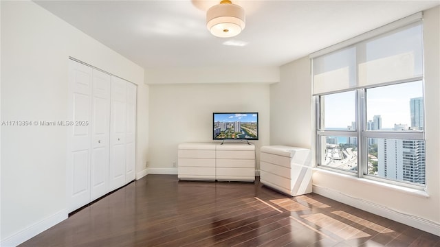 unfurnished bedroom featuring a closet, baseboards, and dark wood-style floors