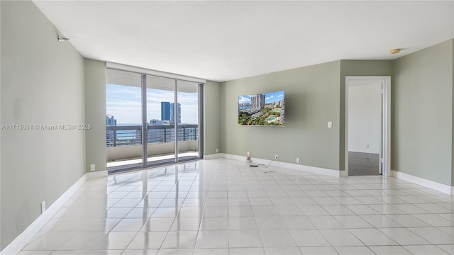 spare room with light tile patterned floors, baseboards, and expansive windows