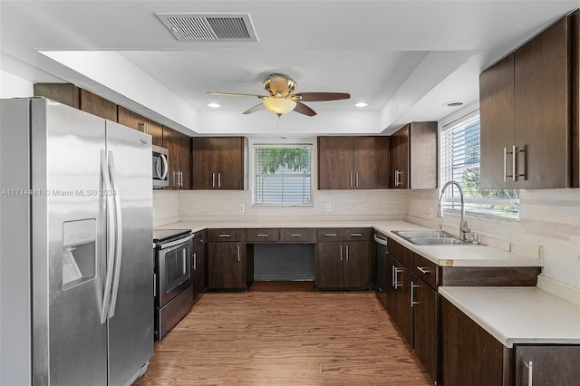 kitchen with dark brown cabinetry, stainless steel appliances, tasteful backsplash, and sink