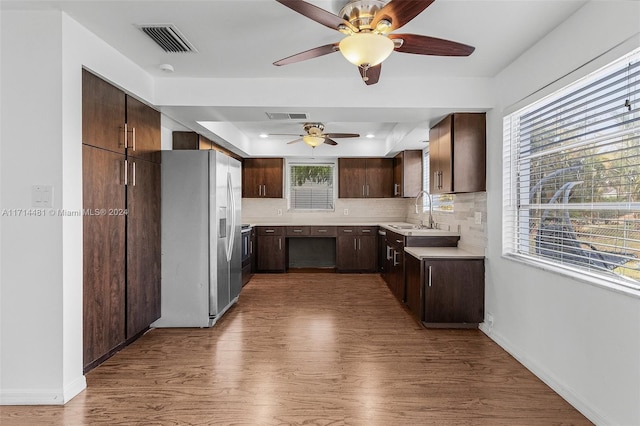 kitchen with appliances with stainless steel finishes, tasteful backsplash, dark brown cabinetry, sink, and hardwood / wood-style floors