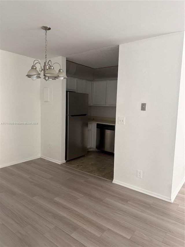 interior space featuring a chandelier, pendant lighting, stainless steel appliances, and light hardwood / wood-style floors